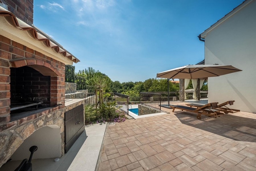 Terrasse couverte avec cheminée extérieure et vue sur la piscine