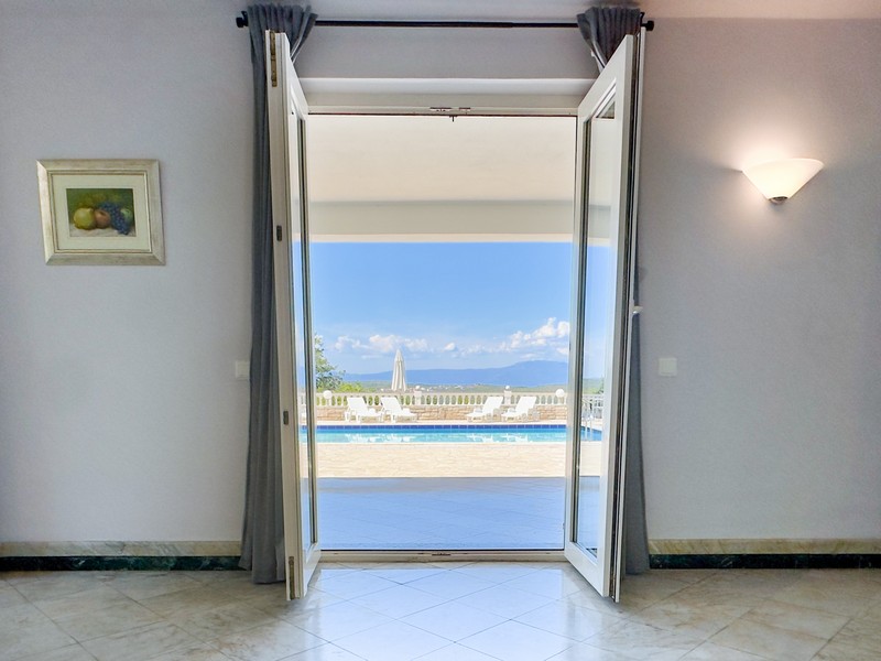 Vue à travers la porte de la terrasse sur la piscine et la mer