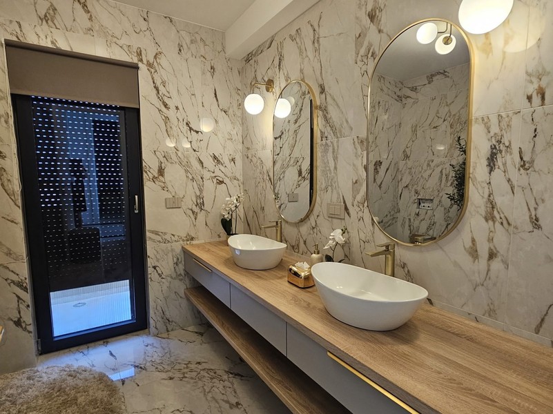 Salle de bains avec murs en marbre et deux vasques à poser