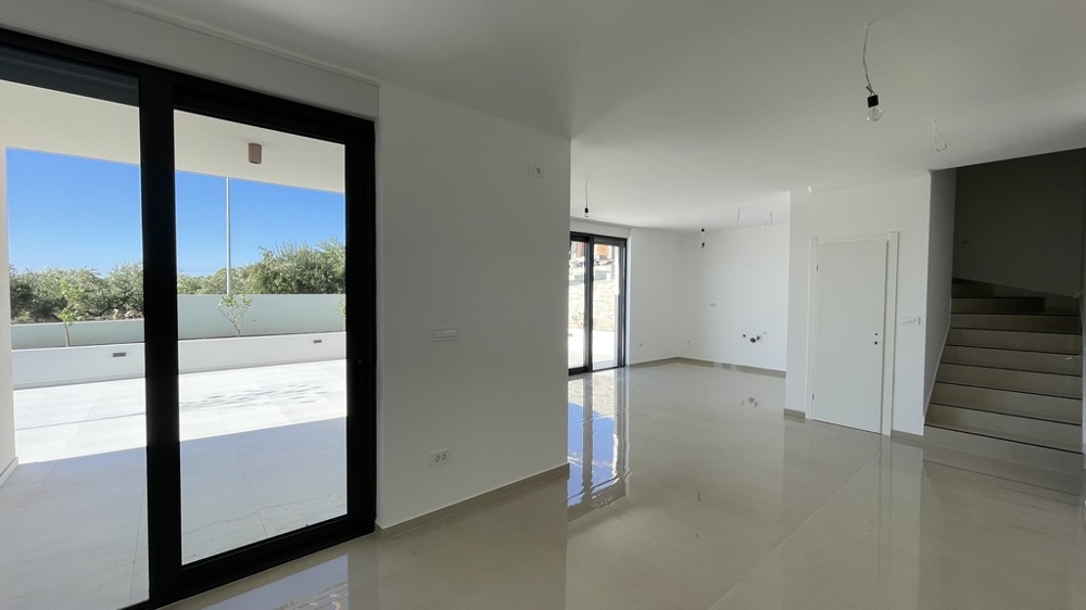 Pièce de vie avec porte donnant sur la terrasse et escalier vers l'étage à Vodice