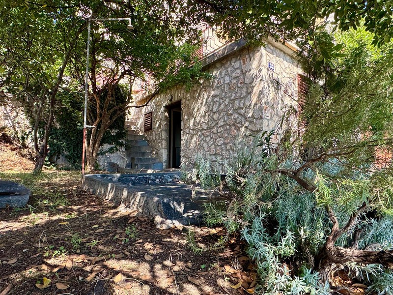 Maison en pierre dans la verdure avec escalier menant à l'entrée