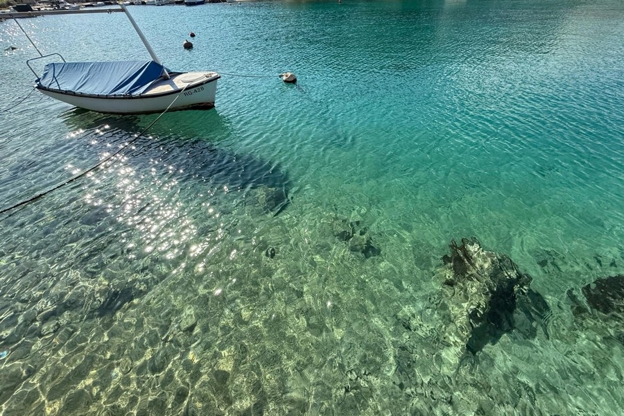 Eau limpide de la baie avec bateau sur la rive