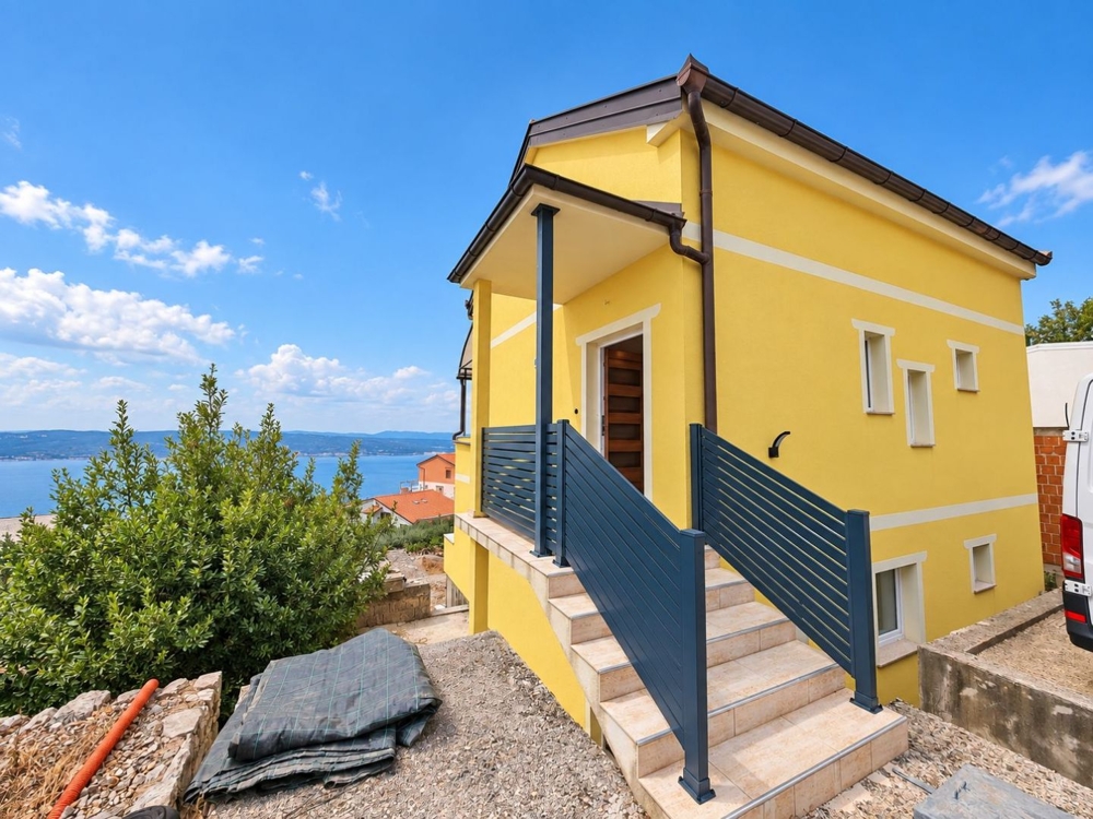 Escalier extérieur menant à l'entrée avec vue sur la mer