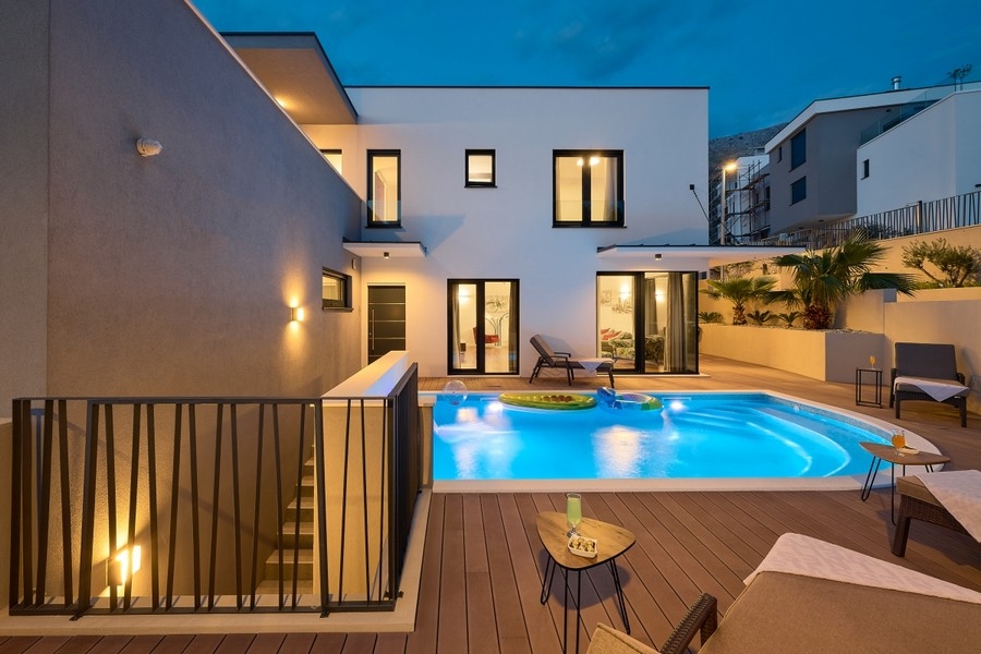 Espace piscine avec terrasse en bois et villa éclairée