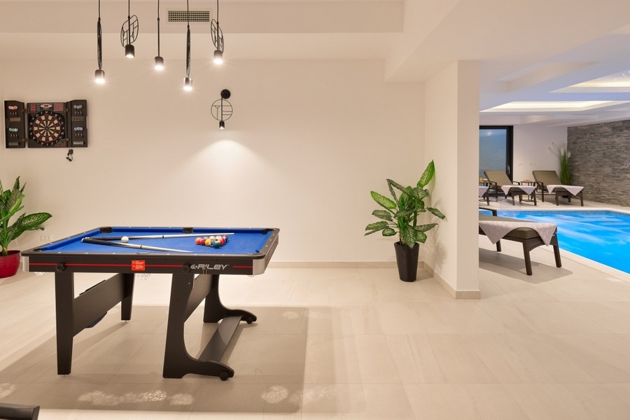 Salle de loisirs avec table de billard près de la piscine intérieure