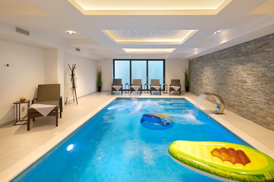 Piscine intérieure éclairée avec mur en pierre naturelle