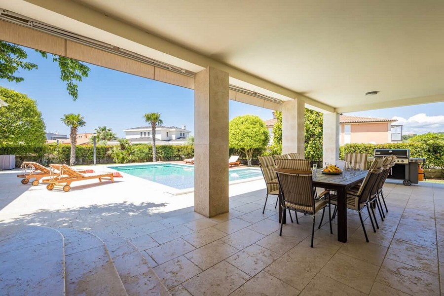 Terrasse couverte avec table à manger au bord de la piscine