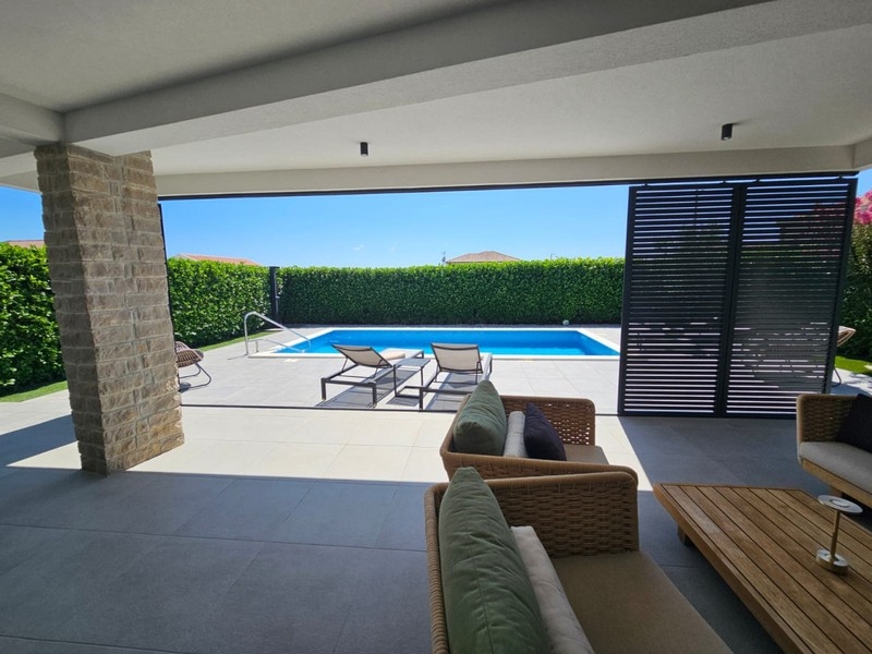 Terrasse couverte avec mobilier lounge et vue sur la piscine