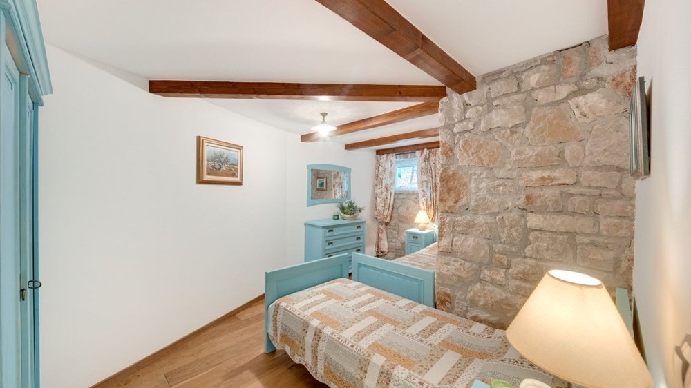 Chambre simple avec mur en pierre et poutres en bois
