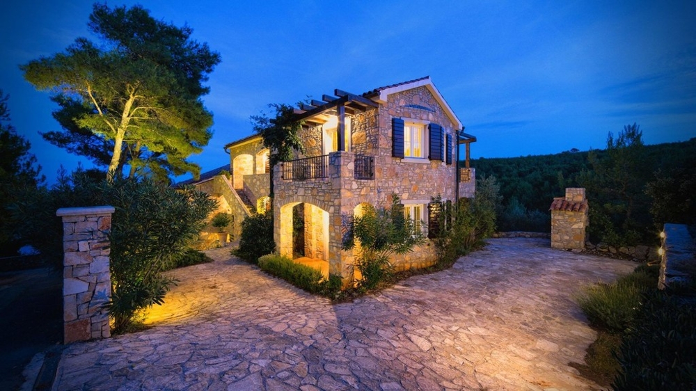 Maison en pierre le soir avec cour éclairée