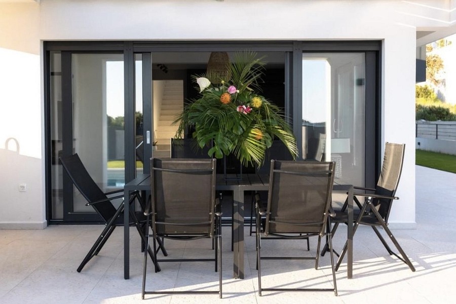 Espace repas sur la terrasse couverte au bord de la piscine