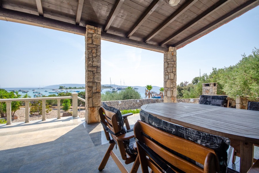 Terrasse couverte avec table à manger et vue mer