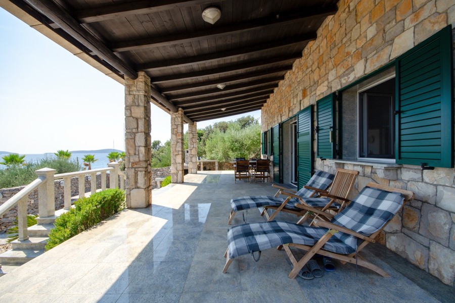 Terrasse couverte avec chaises longues à la villa en pierre