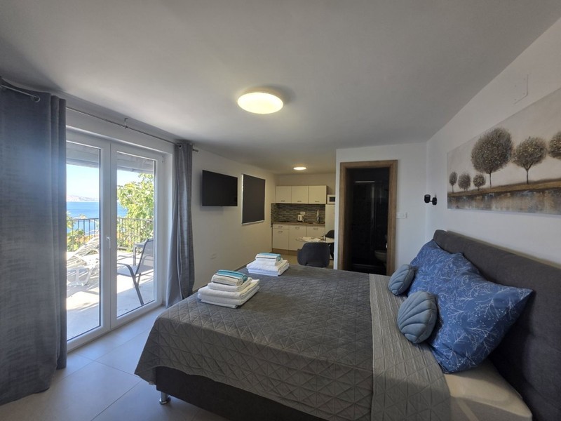 Studio avec lit double et porte donnant sur la terrasse
