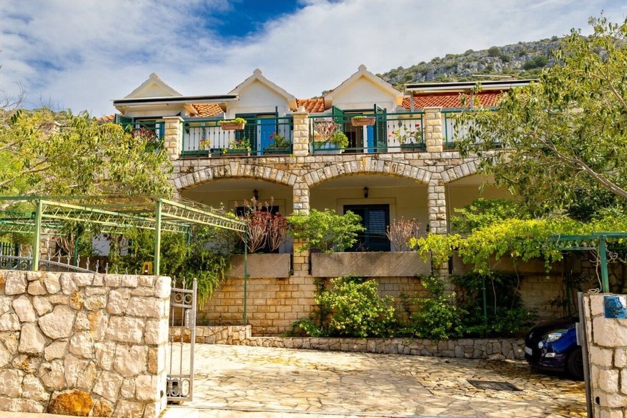 Maison avec mur en pierre et allée dans la verdure