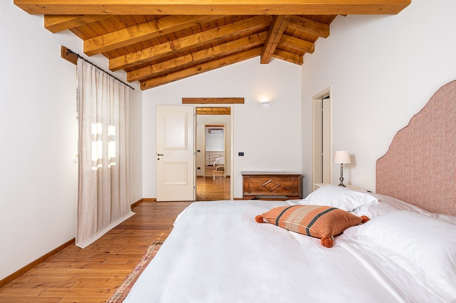 Lit double avec coussin orange et porte ouverte