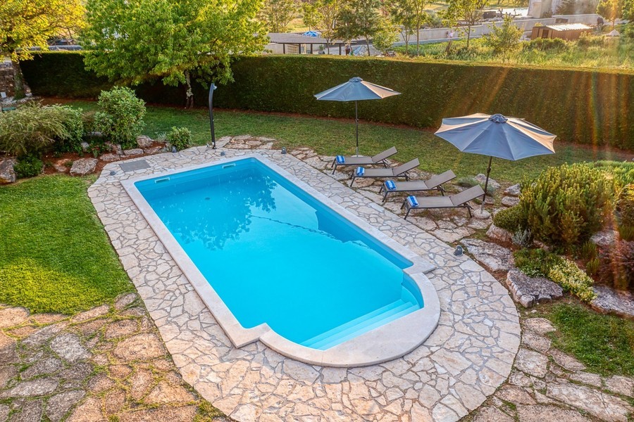 Piscine avec margelle en pierre, transats et parasols vue d'en haut