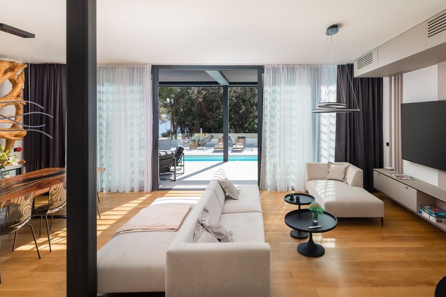 Salon avec canapé et façade vitrée donnant sur la piscine