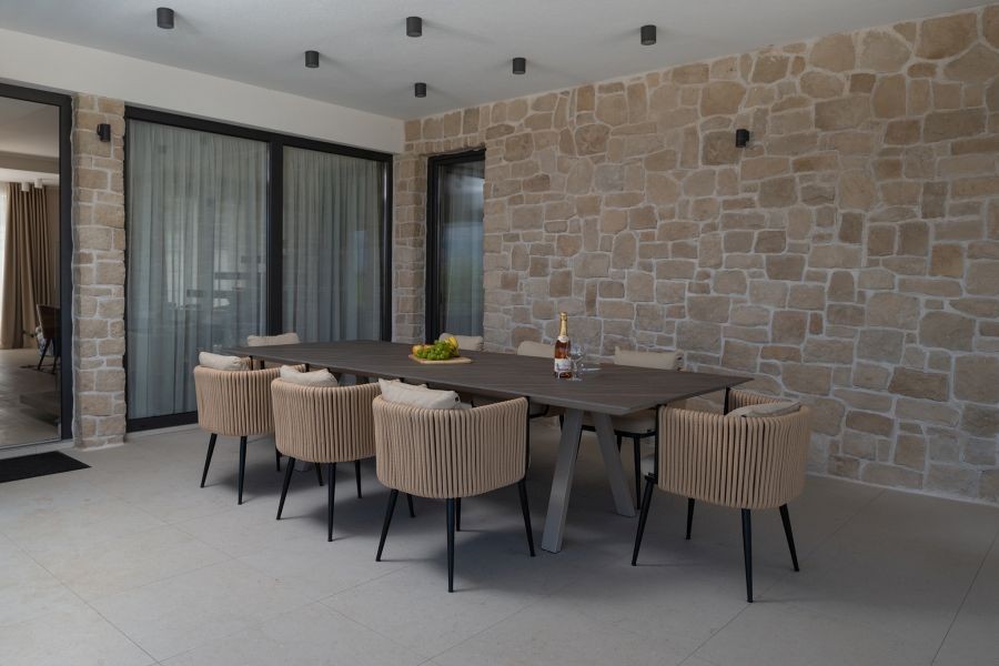 Terrasse couverte avec table à manger et mur en pierre naturelle