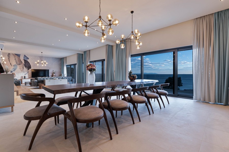 Longue table à manger devant la baie vitrée donnant sur la mer