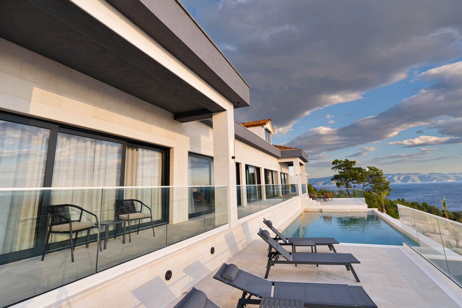 Terrasse avec garde-corps en verre et transats au bord de la piscine