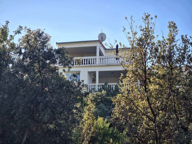 Façade de la maison avec balcon entre les oliviers