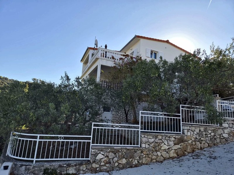 Maison sur la pente avec balcons et clôture donnant sur la route