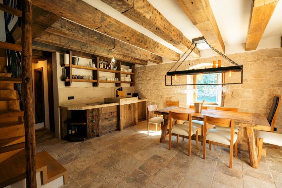 Cuisine-séjour avec poutres en bois, murs en pierre et table à manger