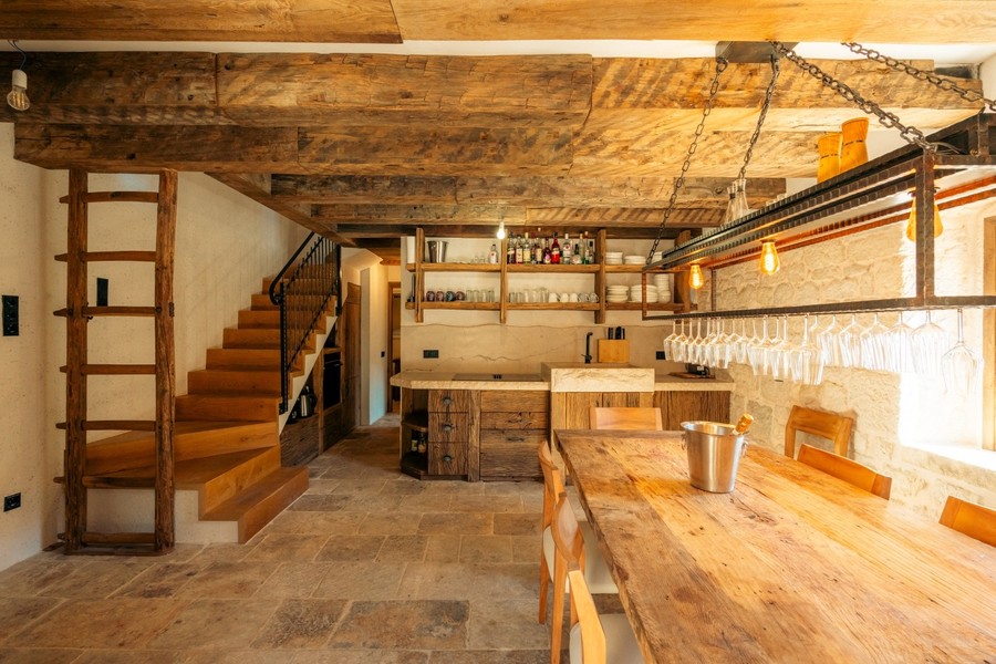 Pièce de vie avec escalier, étagères et plafond à poutres en bois