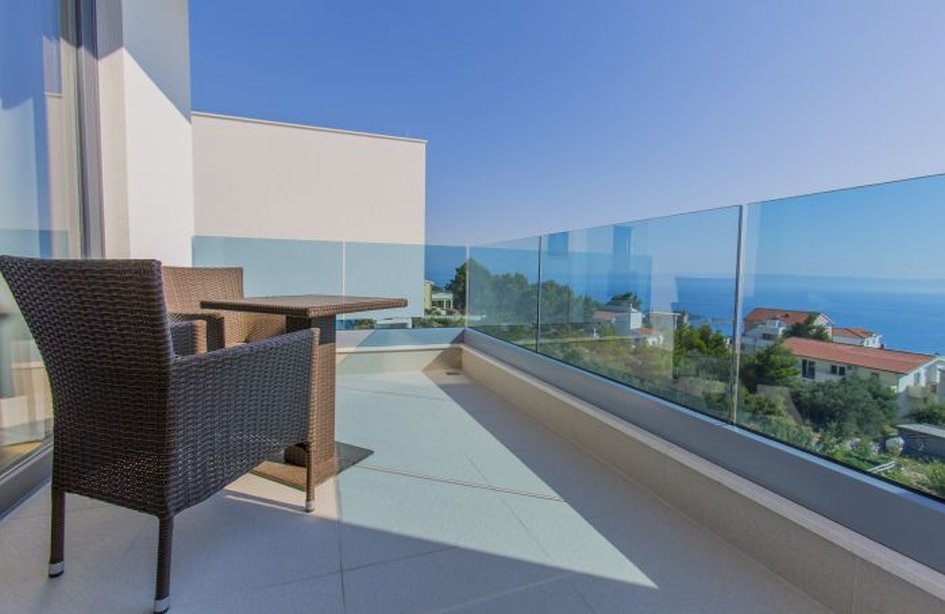 Balcon avec garde-corps en verre et fauteuil en osier au-dessus de la côte