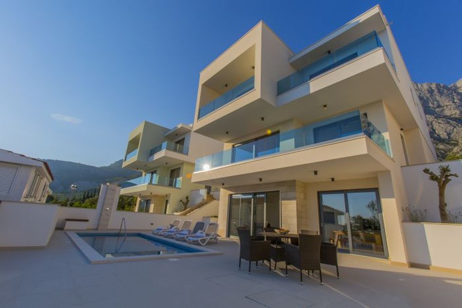 Villas blanches avec piscine et bains de soleil devant les montagnes