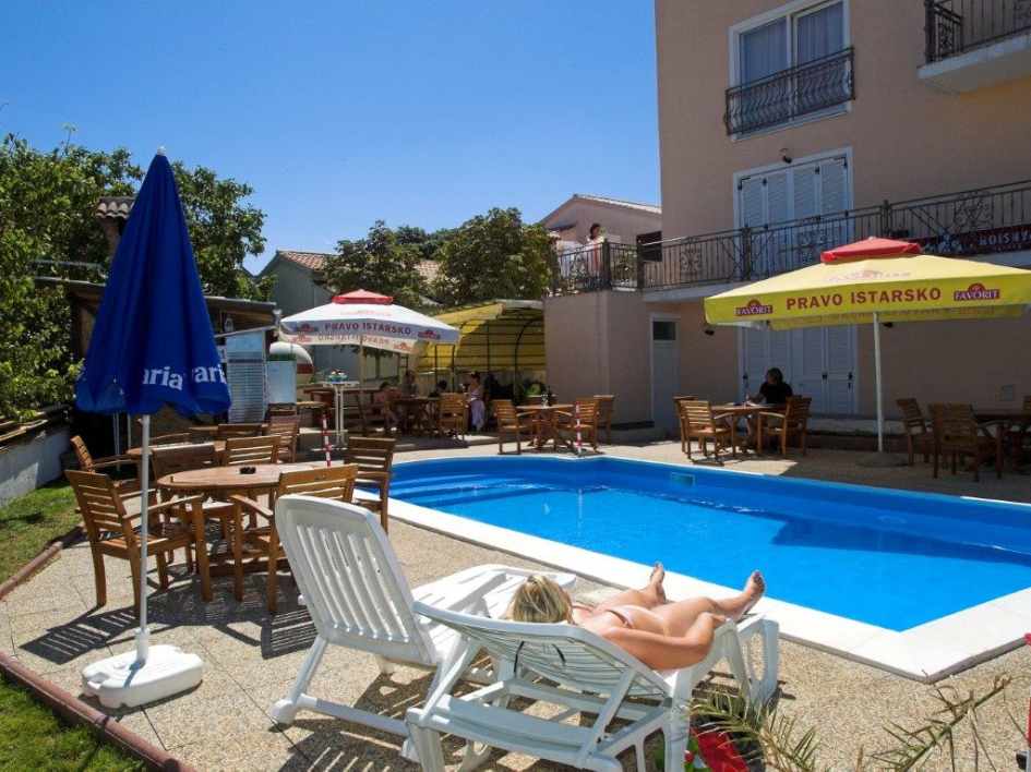 Piscine avec parasols et bains de soleil dans une pension-hôtel près de Pula