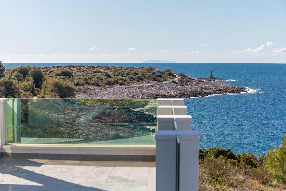 Vue par-dessus le garde-corps en verre sur la côte rocheuse avec phare