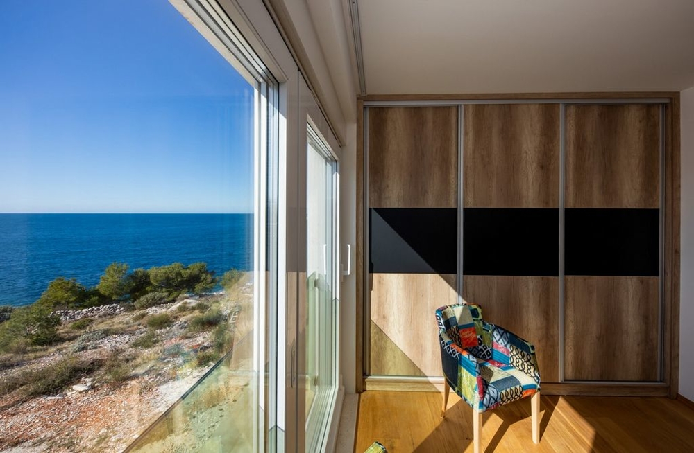 Pièce avec placard coulissant et fenêtre du sol au plafond donnant sur la mer
