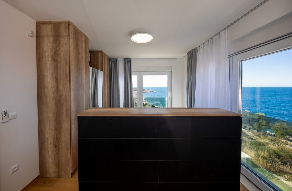 Chambre avec commode et rideaux devant la vue sur la mer
