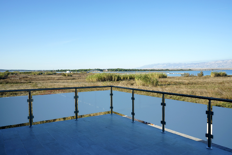Terrasse avec garde-corps en verre et vue au-dessus des roseaux sur la lagune