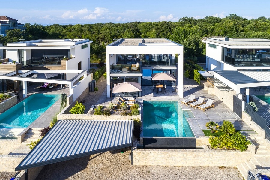 Vue aérienne de plusieurs villas avec piscines et parasols