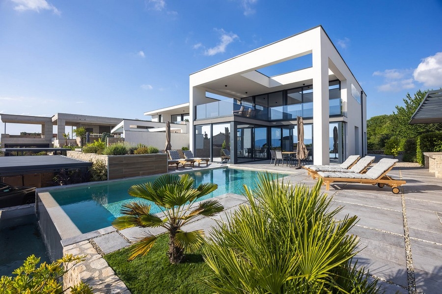 Villa avec piscine et palmiers dans un massif de gravier sous un ciel bleu